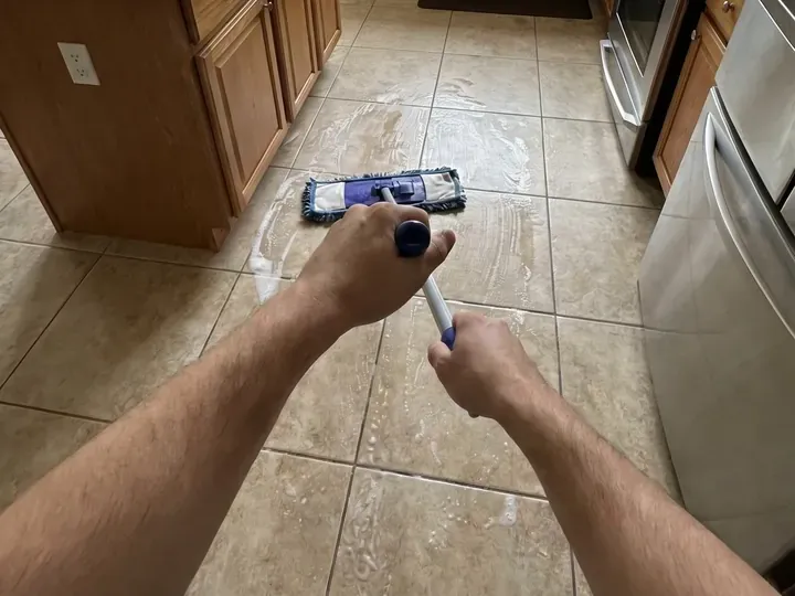 Hands mopping a kitchen floor